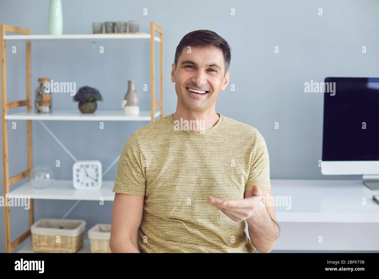 Geschäftsfrau in lässigem T-Shirt lächelnd, die Kamera zu Hause im Büro anblickend Stockfoto
