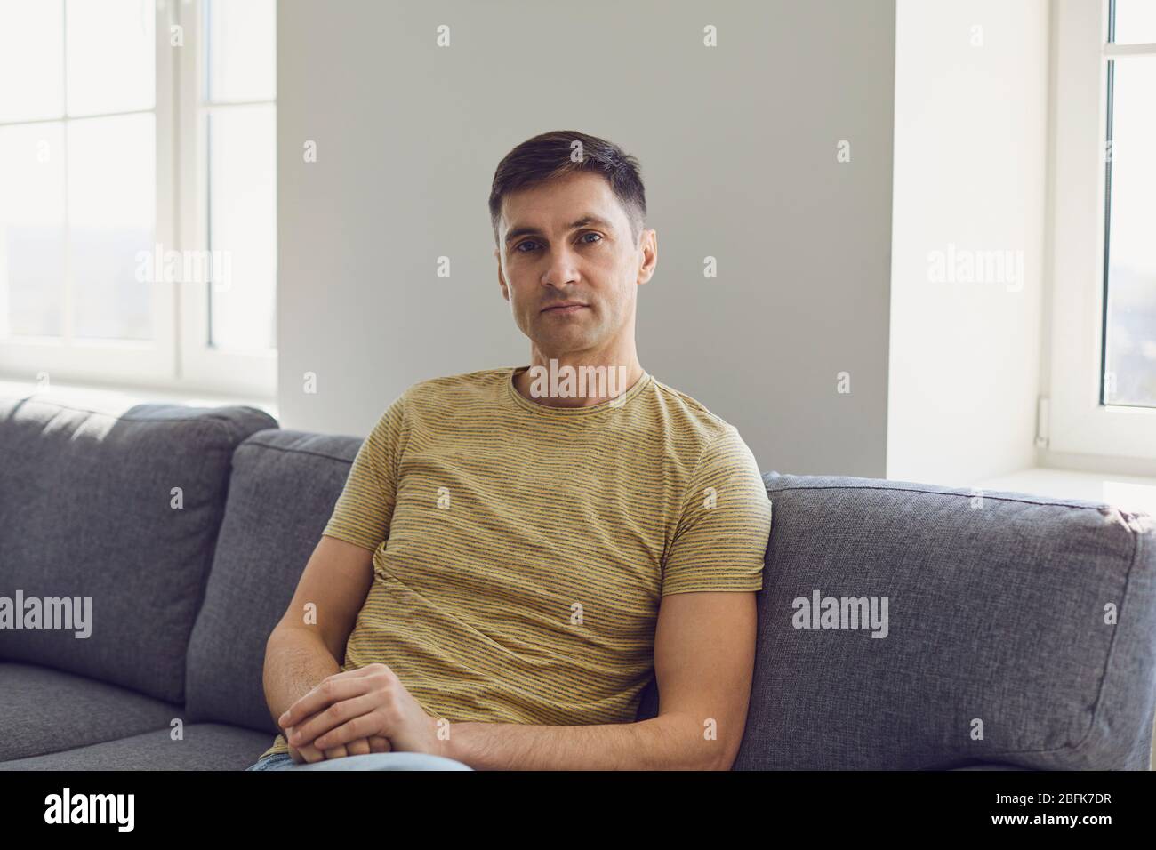 Geschäftsmann in lässigem T-Shirt ernst Blick auf die Kamera zu Hause im Büro Stockfoto