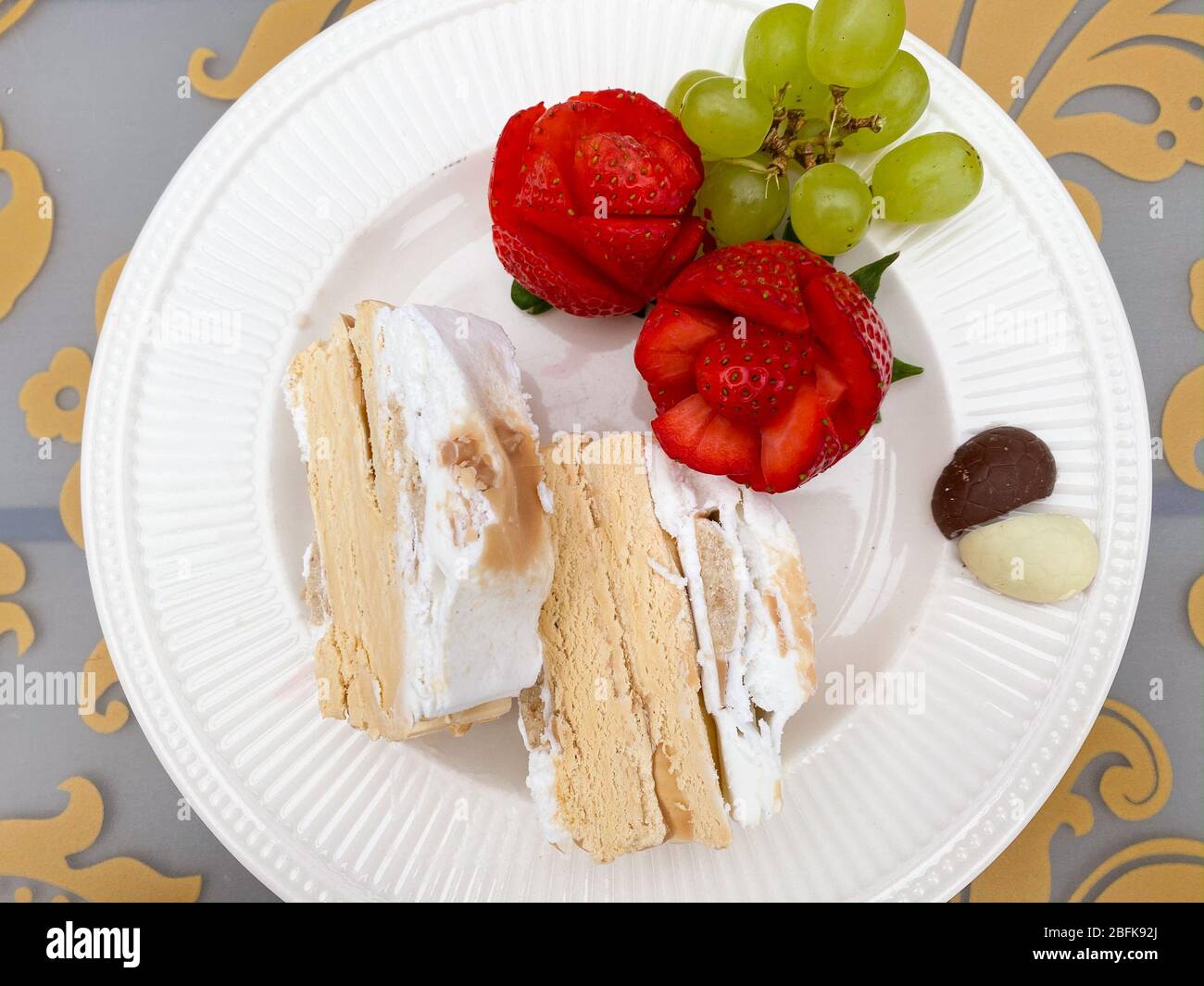 Dessertplatte mit Karamell-Eiskuchen, roten Rose Erdbeeren, grünen Trauben und Pralinen in Herzform Stockfoto