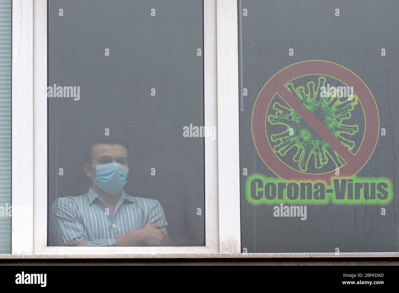 Junger Mann mit Gesichtsmaske, krank mit COVID-19, Blick durch das Fenster quaranteed im Krankenhaus.Schutz vor Coronavirus oder covid-19 con Stockfoto