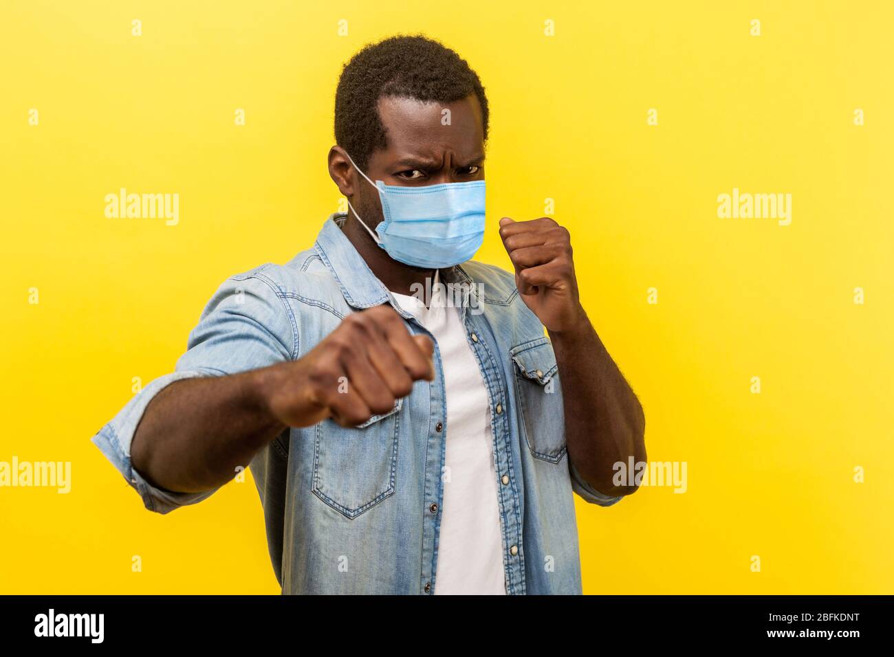 Bereit für den Kampf gegen Coronavirus. Porträt des aggressiven Mannes mit chirurgischen medizinischen Maske in defensiver Haltung, geballte Fäuste, bedrohlich Stockfoto