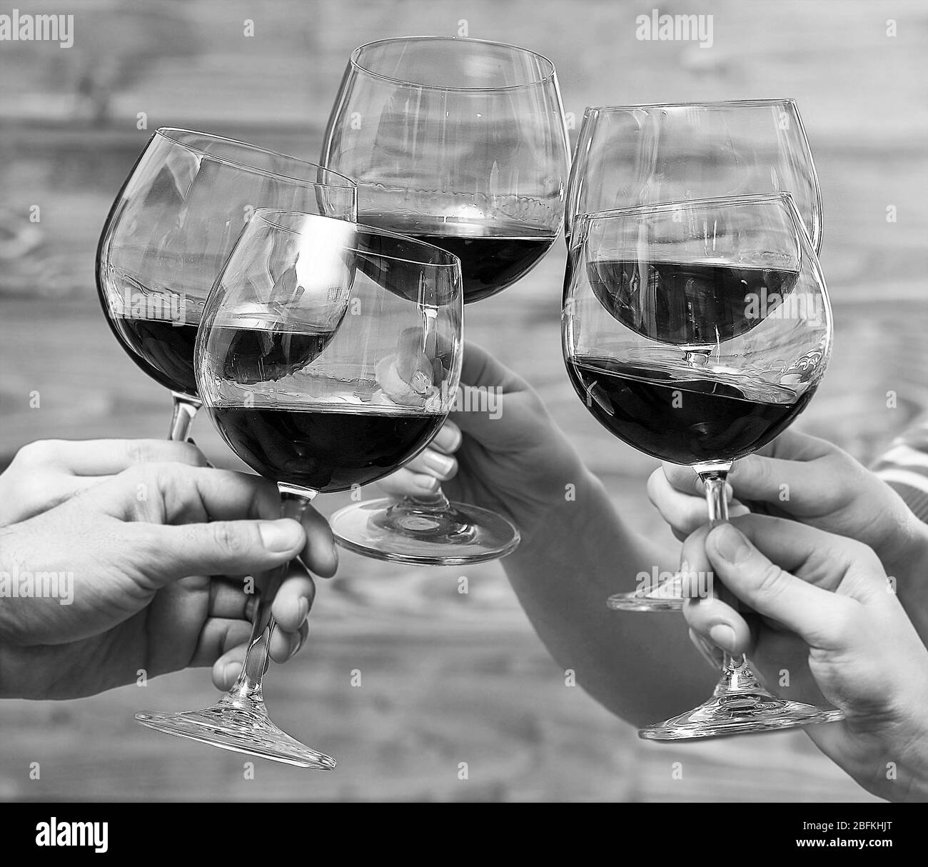 Anklirrender Rotwein in den Händen, schwarz-weiß Retro-Stilisierung Stockfoto