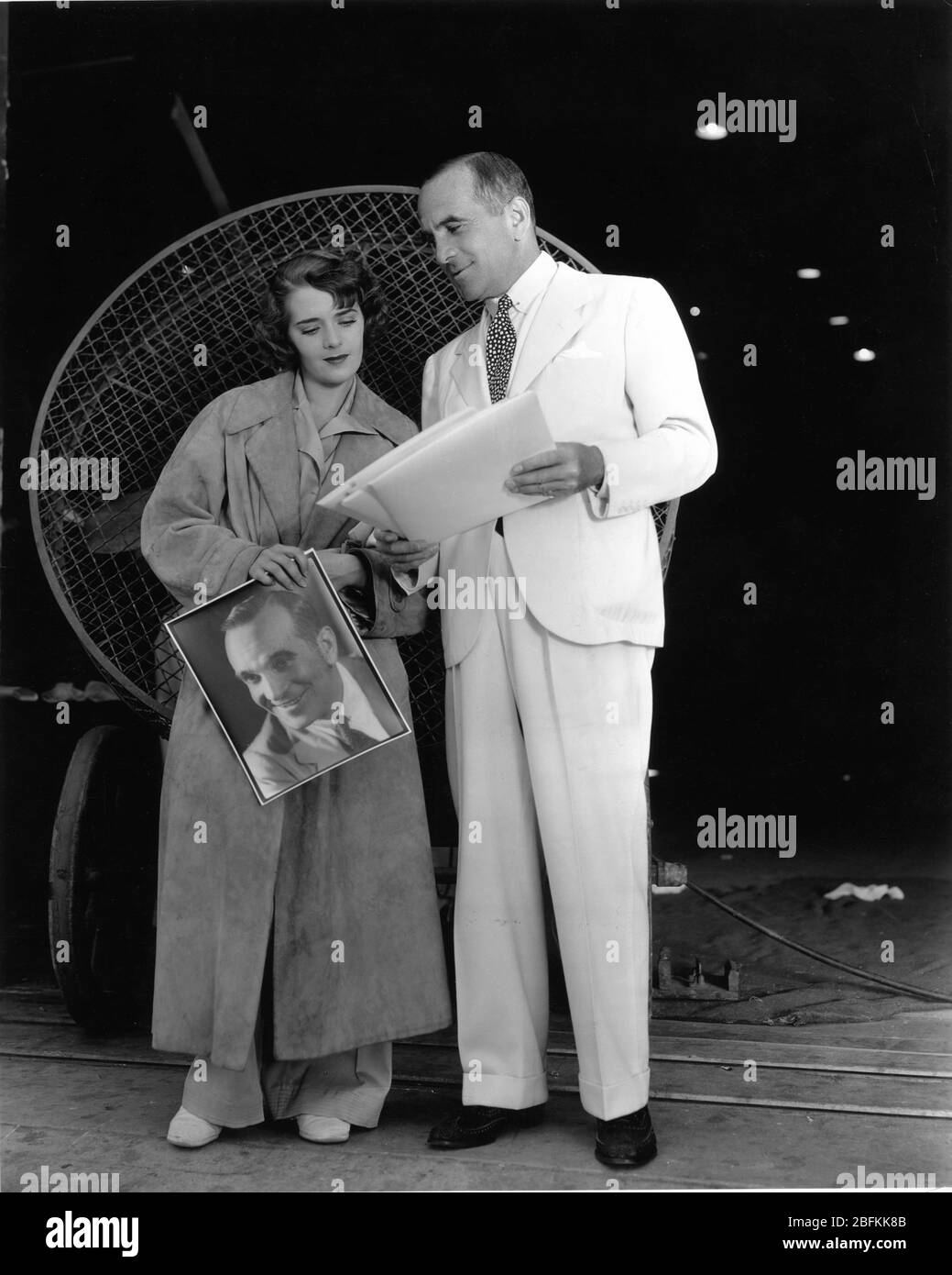 AL JOLSON zeigt seiner Frau RUBY KEELER Fotos von sich am Set Candid auf Warner Bros. Studio Lot Juni 1934 Warner Bros. Publicity Stockfoto