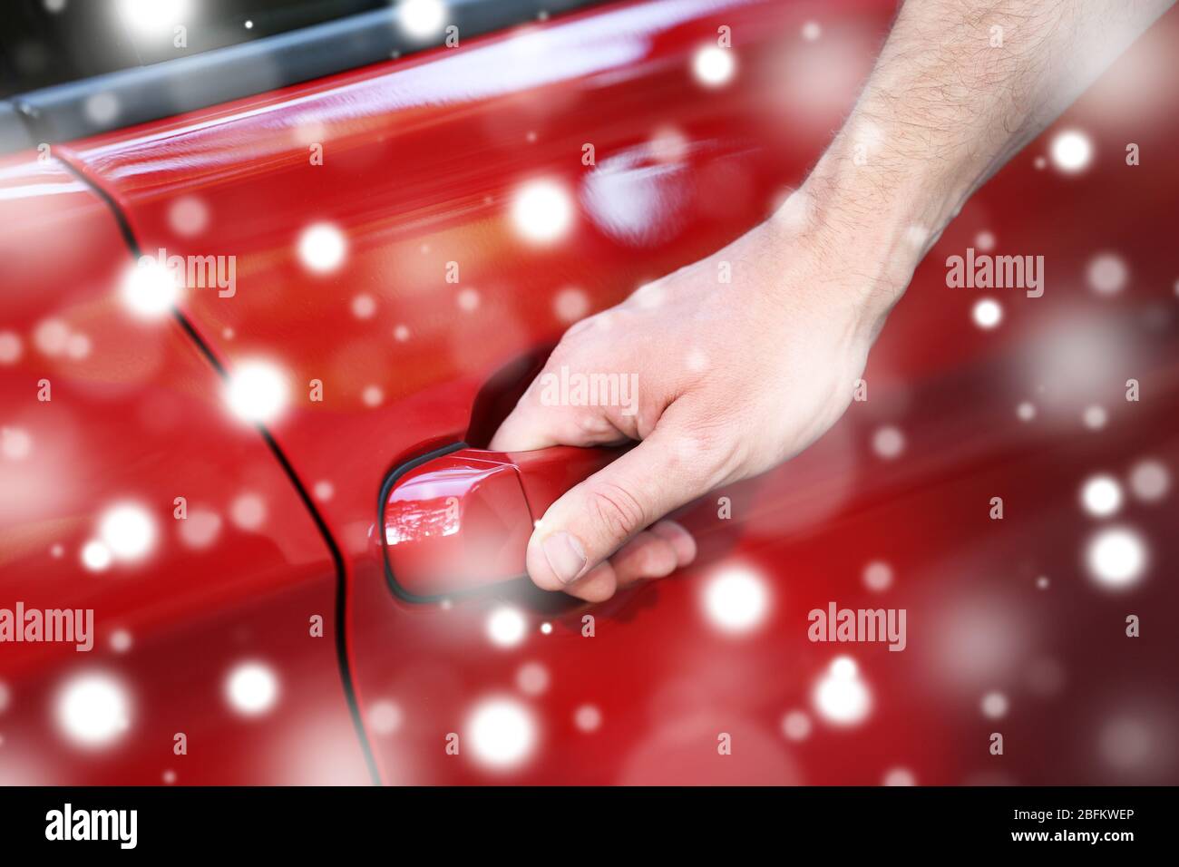 Männliche Hand hält die Tür Griff des roten Autos über Schnee-Effekt Stockfoto