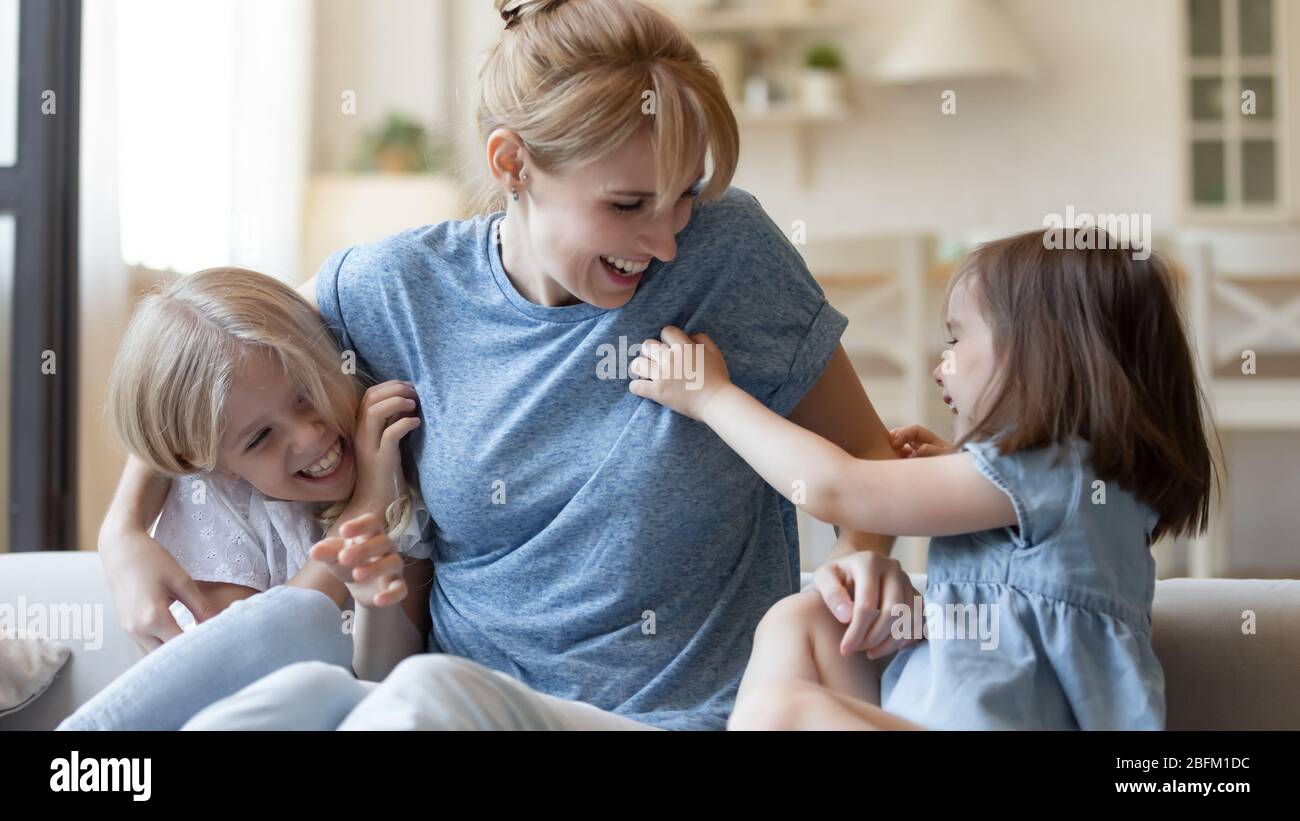 Nahaufnahme glücklich kleine Schwestern kitzeln junge Mutter. Stockfoto