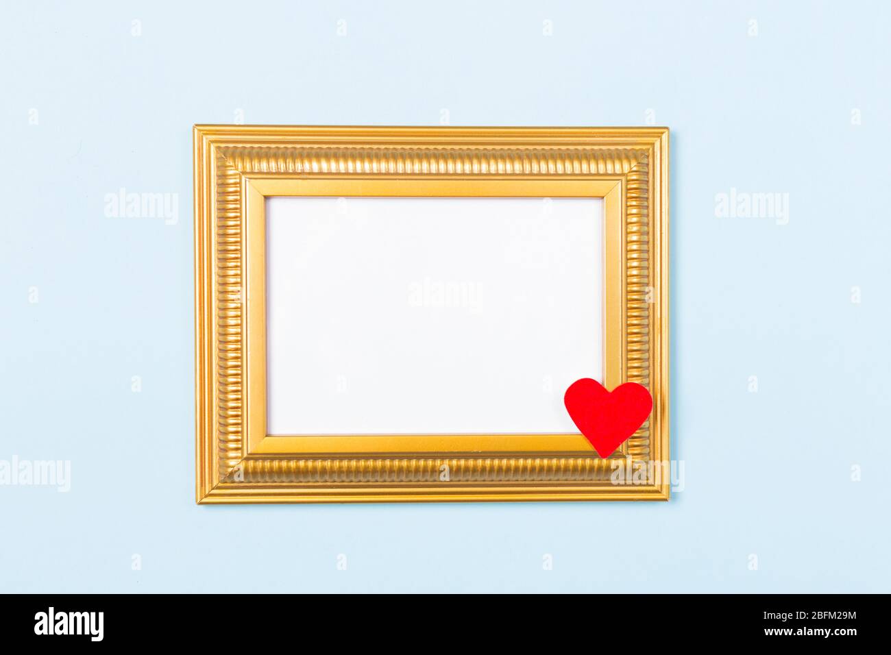 Golden Frame leere Bild mit rotem Herz auf hellblauem Hintergrund. Kopieren Sie Speicherplatz freien Speicherplatz für Text. Konzept der Urlaubskarte. Mock-up. Gruß Stockfoto