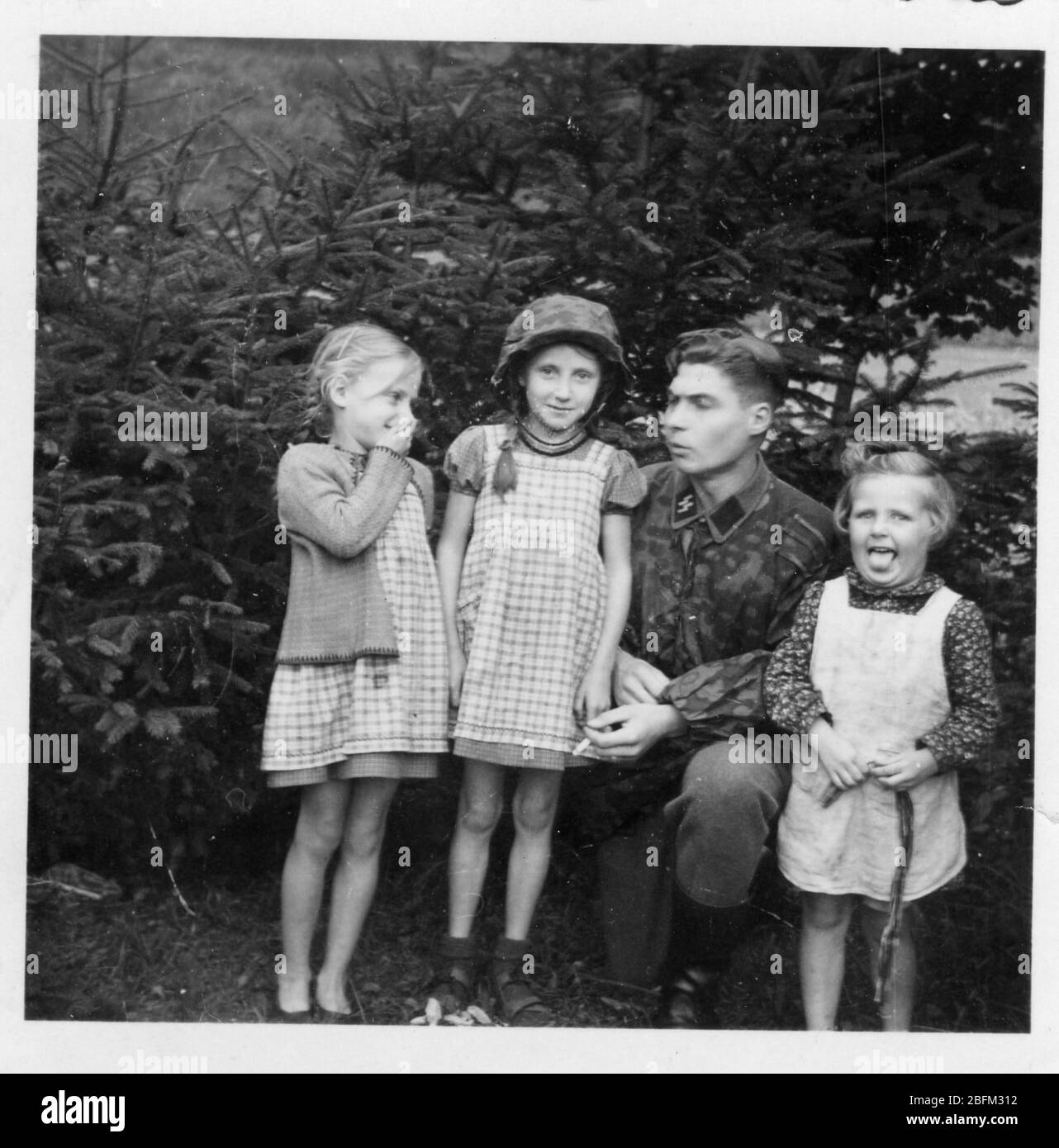 2. Weltkrieg, SS-Soldat in mimetischer Uniform mit 3 kleinen Mädchen in Deutschland, wahrscheinlich Dresden Stockfoto