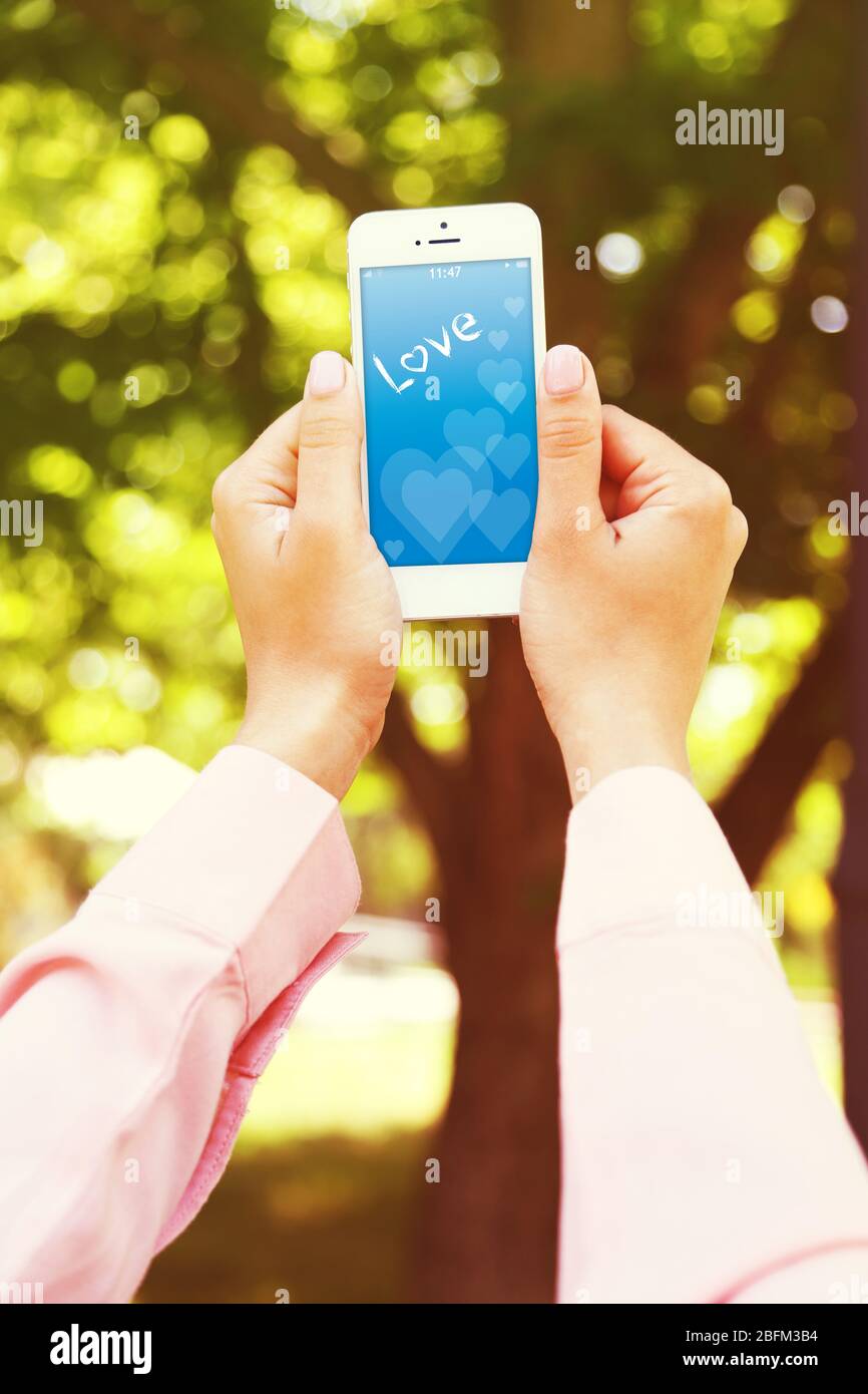 Junge Frau mit Smartphone mit romantischen Bildschirmschoner Stockfoto