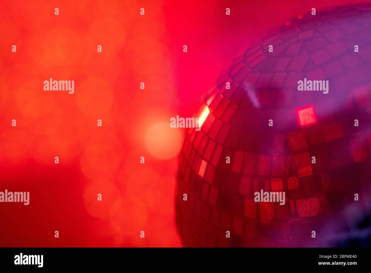Teil der großen funkelnden und rotierenden Disco-Ball in Nachtclub vor rot rauchigen Hintergrund mit Copyspace für Ihre Notiz oder Werbung Stockfoto