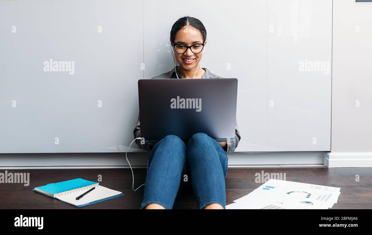 Frau Videoanrufe auf dem Küchenboden. Lächelnder Unternehmer, der am Laptop arbeitet. Stockfoto