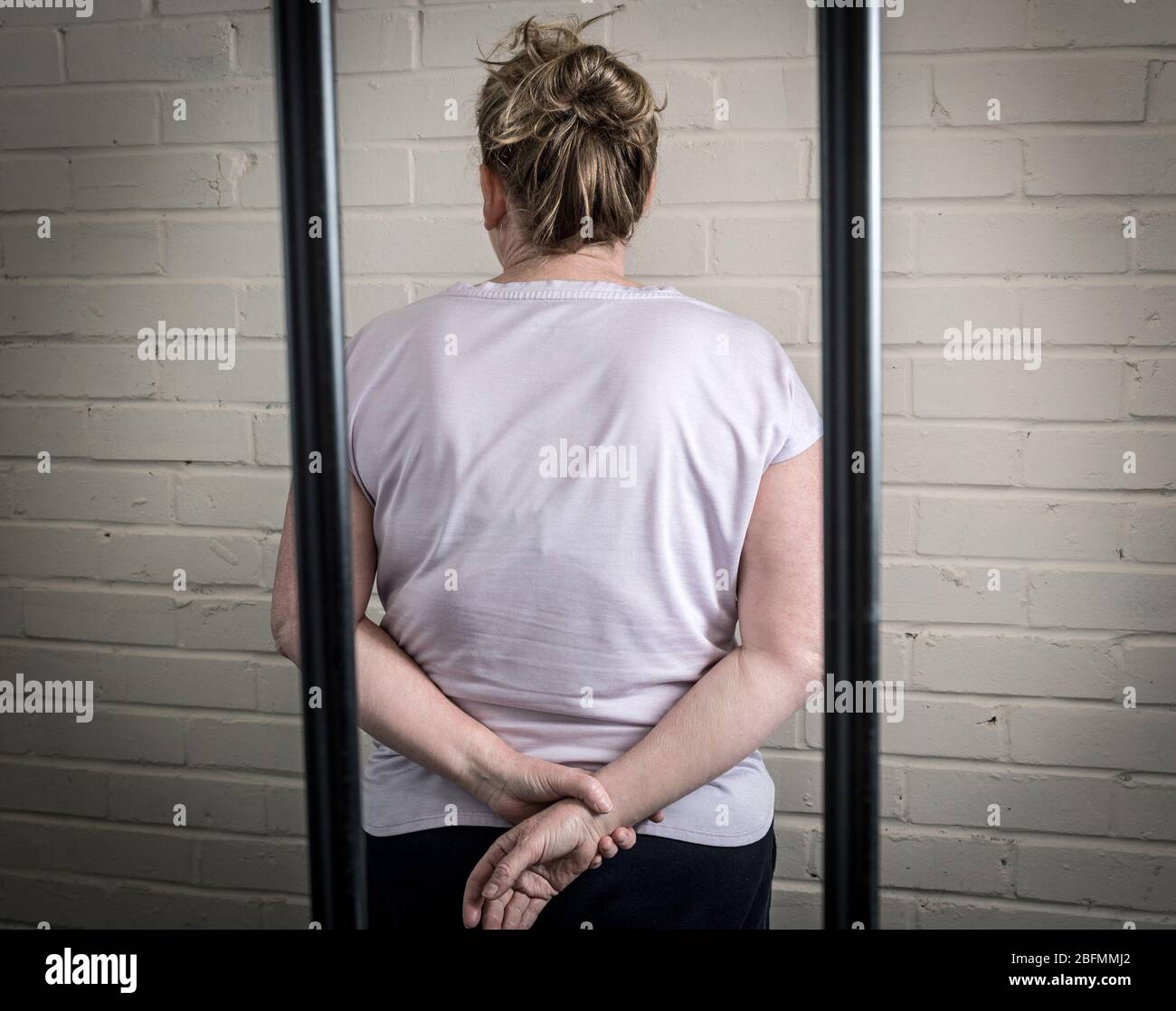 Eine weibliche Gefangene hinter Gittern in einem Frauengefängnis. Bild nach Modell gestellt. Stockfoto