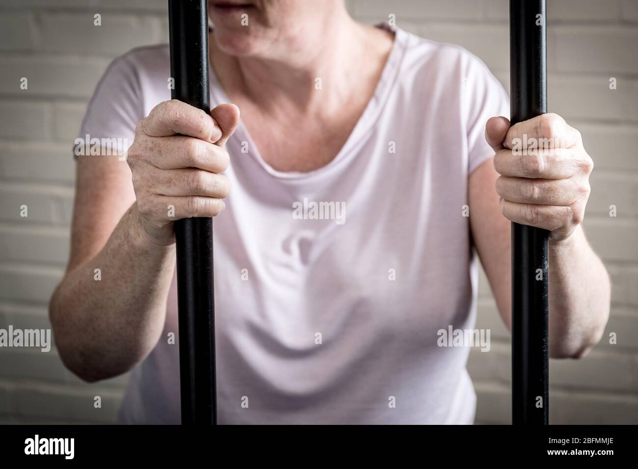 Eine weibliche Gefangene hinter Gittern in einem Frauengefängnis. Bild nach Modell gestellt. Stockfoto