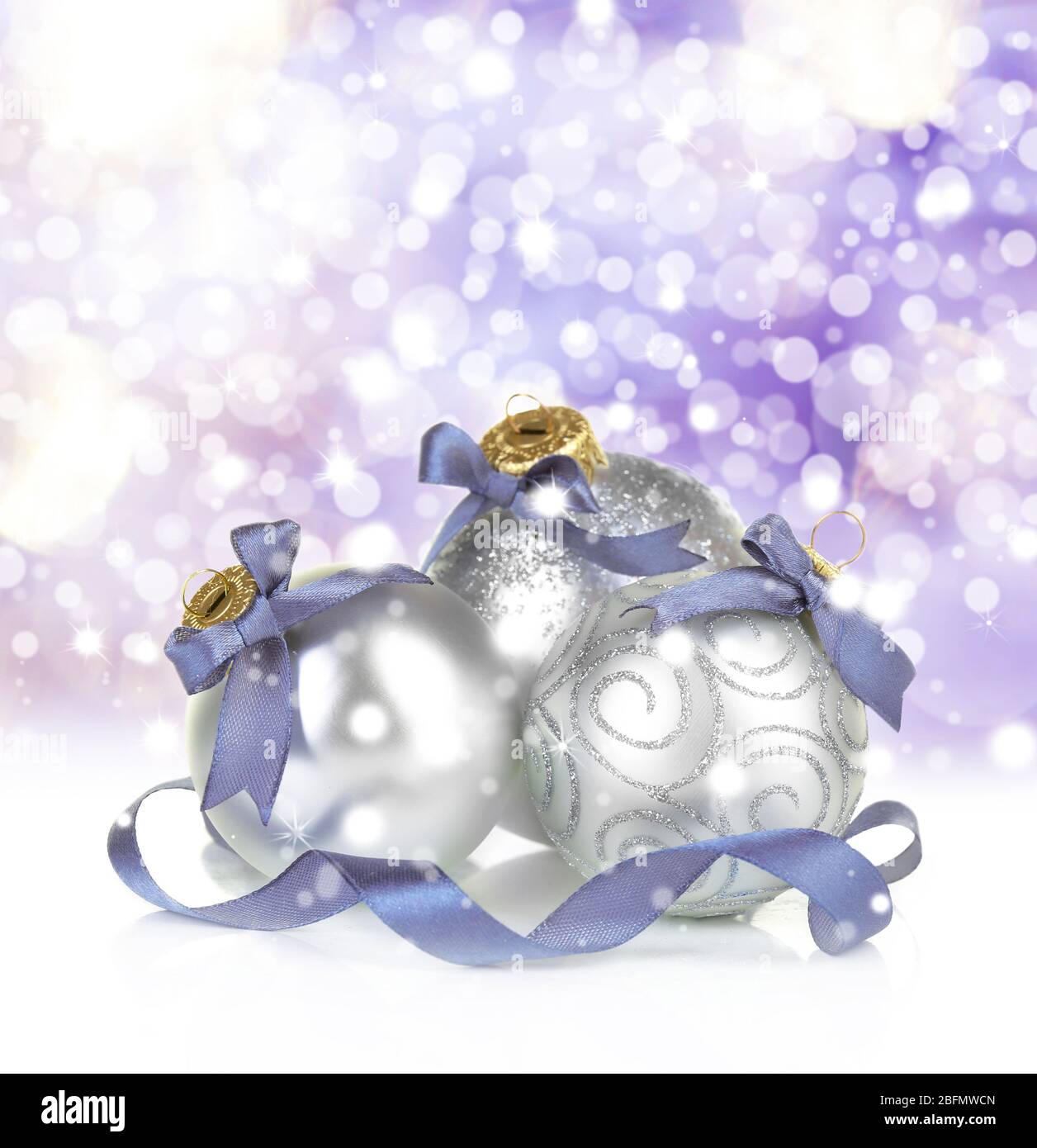 Weihnachtskugeln auf glänzendem lila Hintergrund Stockfoto