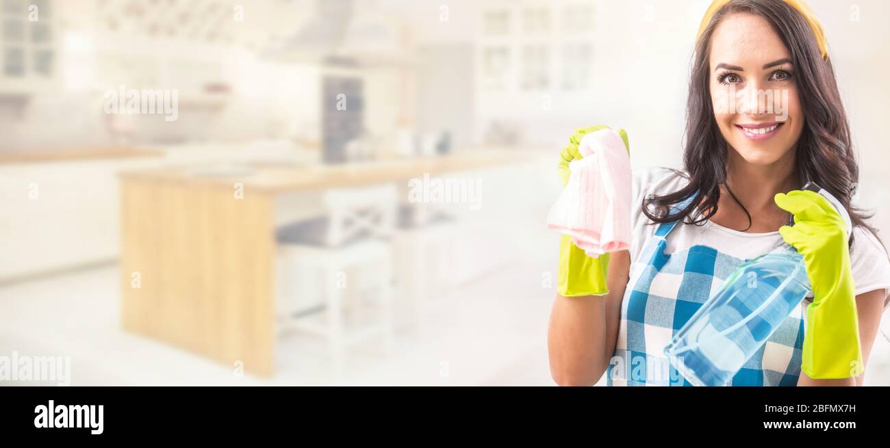 Banner-Ansicht einer lächelnden schönen Frau in Schürze hält Waschmittel und Putzlappen in den Händen in Gummihandschuhen im rechten Drittel des Bildes w Stockfoto