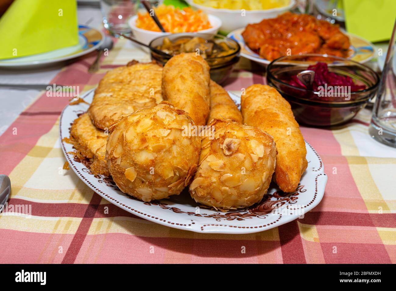 Ein Haufen gebratener, gefüllter polnischer Kroketten, die auf einem dekorierten Tisch liegen, sichtbare Pilze und Rüben. Stockfoto