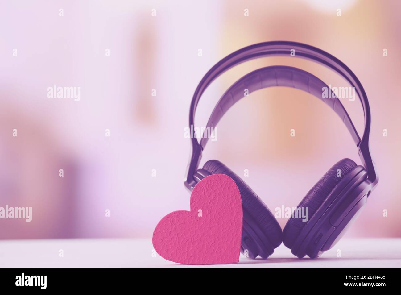 Schwarze Kopfhörer mit Herz auf unscharfarbetem Hintergrund Stockfoto