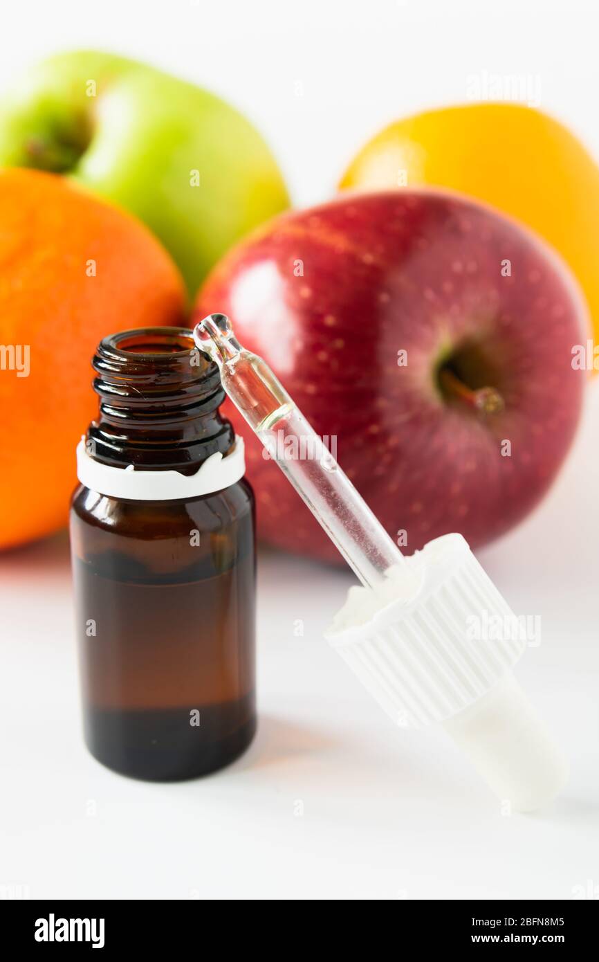 Kosmetisches Konzept, Glasflasche mit Serum mit Alpha-Hydroxy-Säuren auf einem Hintergrund von Früchten Stockfoto