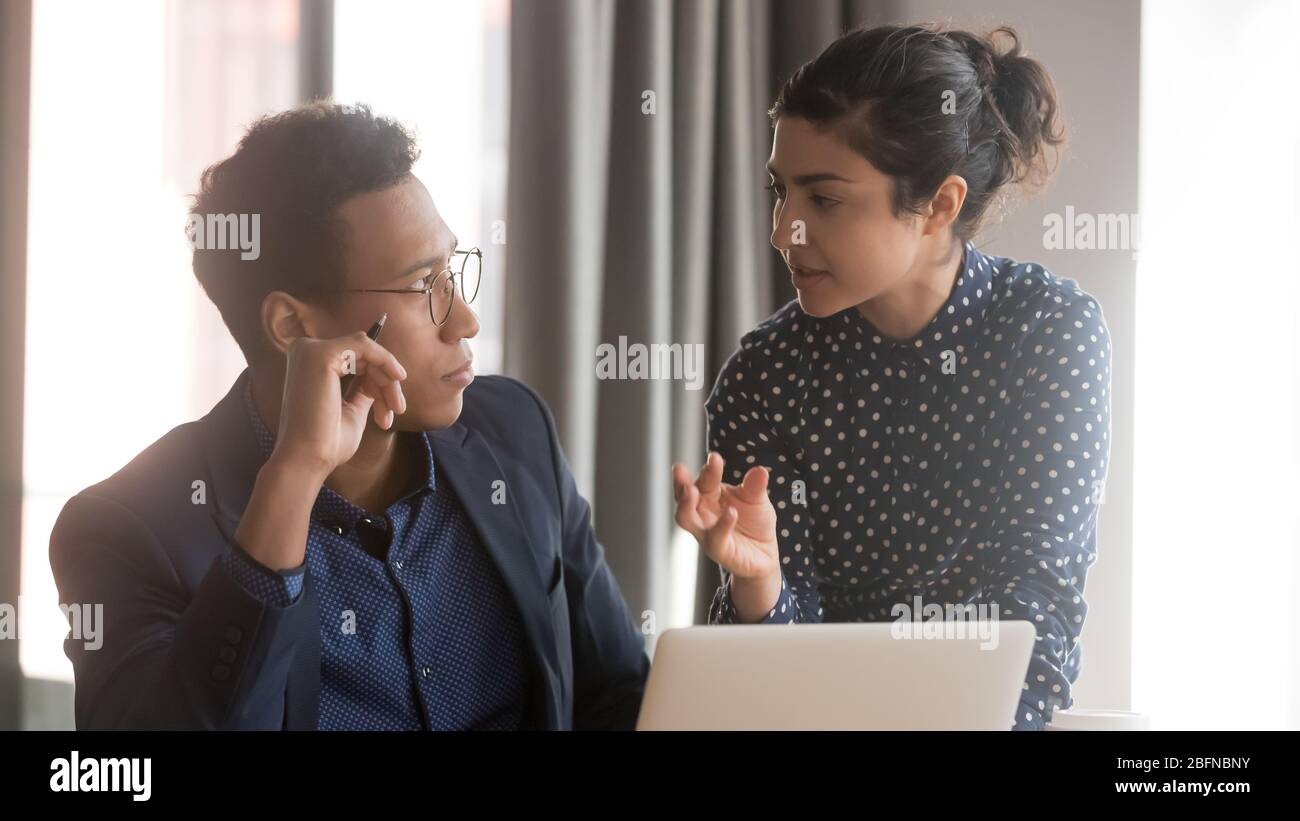 Indische Teamleiterin, die Ideen mit einem afrikanischen Kollegen teilt Stockfoto