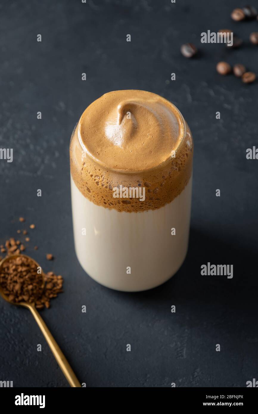 Dalgona schaumig Kaffee in Glas auf schwarz. Trend koreanisch Iced Coffee Latte Drink mit Schaum von Instant-Kaffee. Vertikale Aufnahme. Stockfoto
