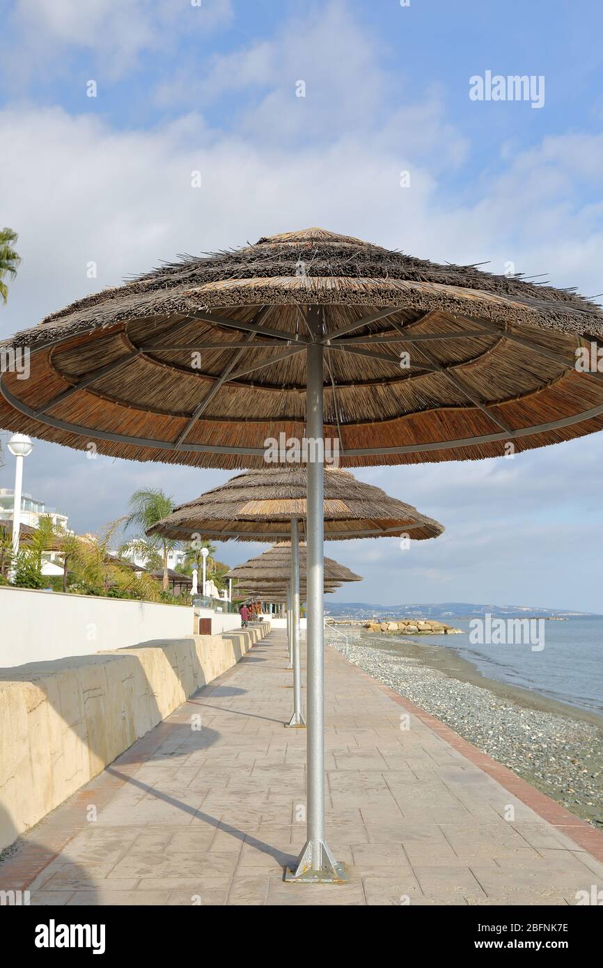 Schilfstrandschirme an der Promenade entlang des Strandes und des Mittelmeers, leer, ohne Menschen, sonniger Urlaubstag. Stockfoto