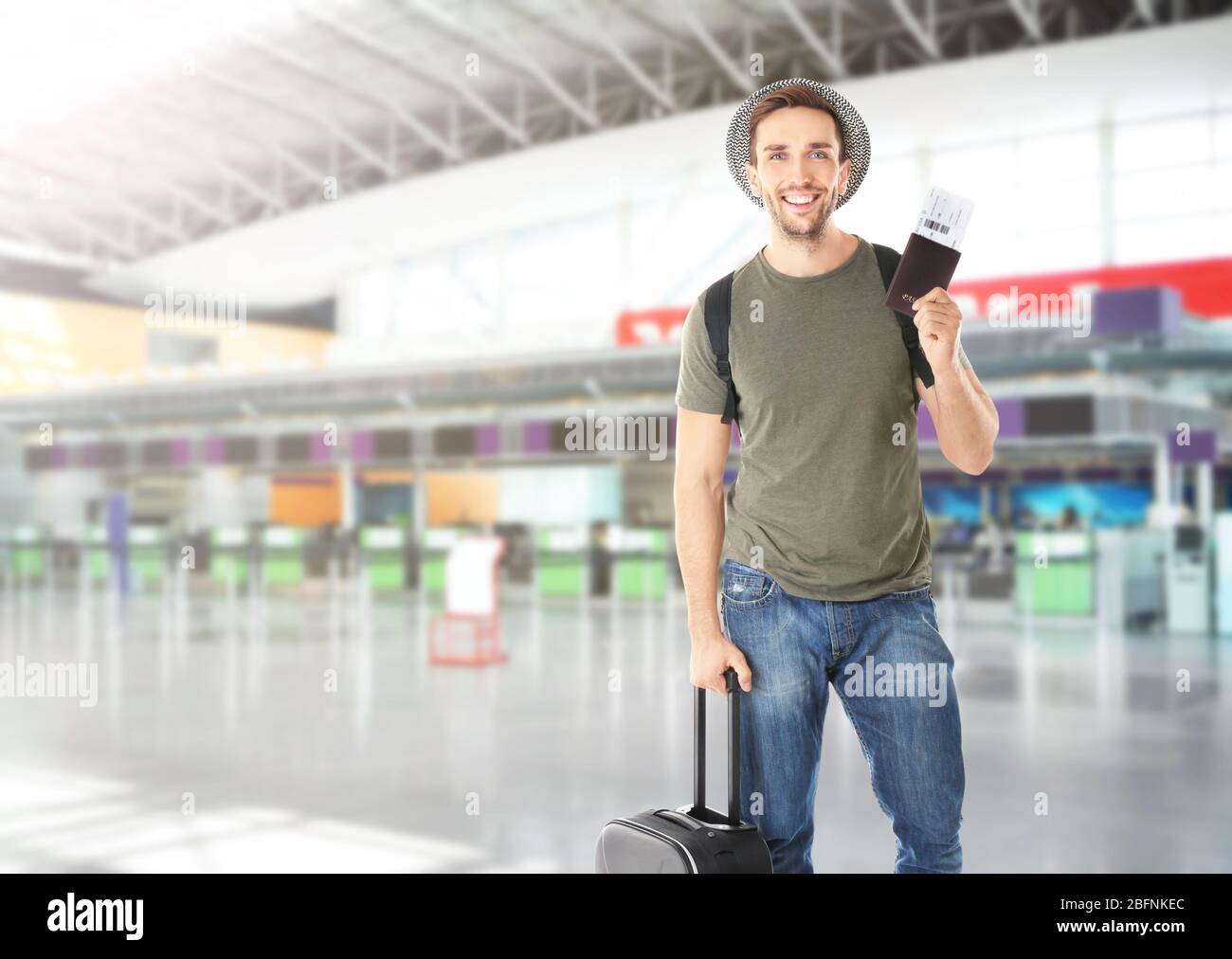Junger Mann mit Pass, Ticket und Gepäck am Flughafen Stockfoto