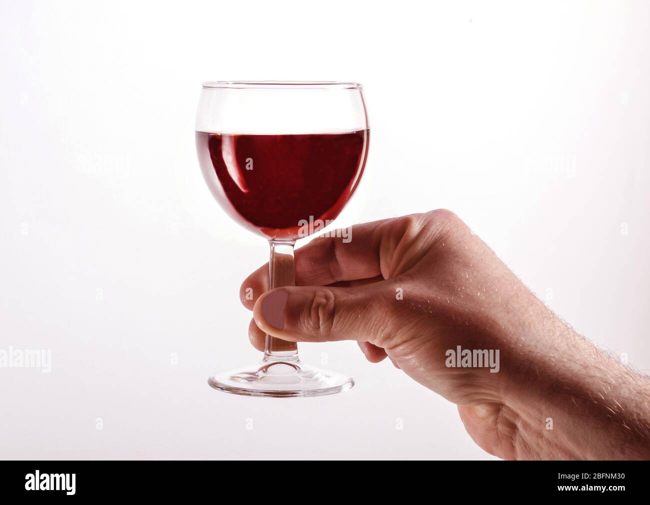 Ein Mann hebt einen Glaskoblett mit Rotwein. Isoliert auf einem weißen. Für Standorte. Stockfoto