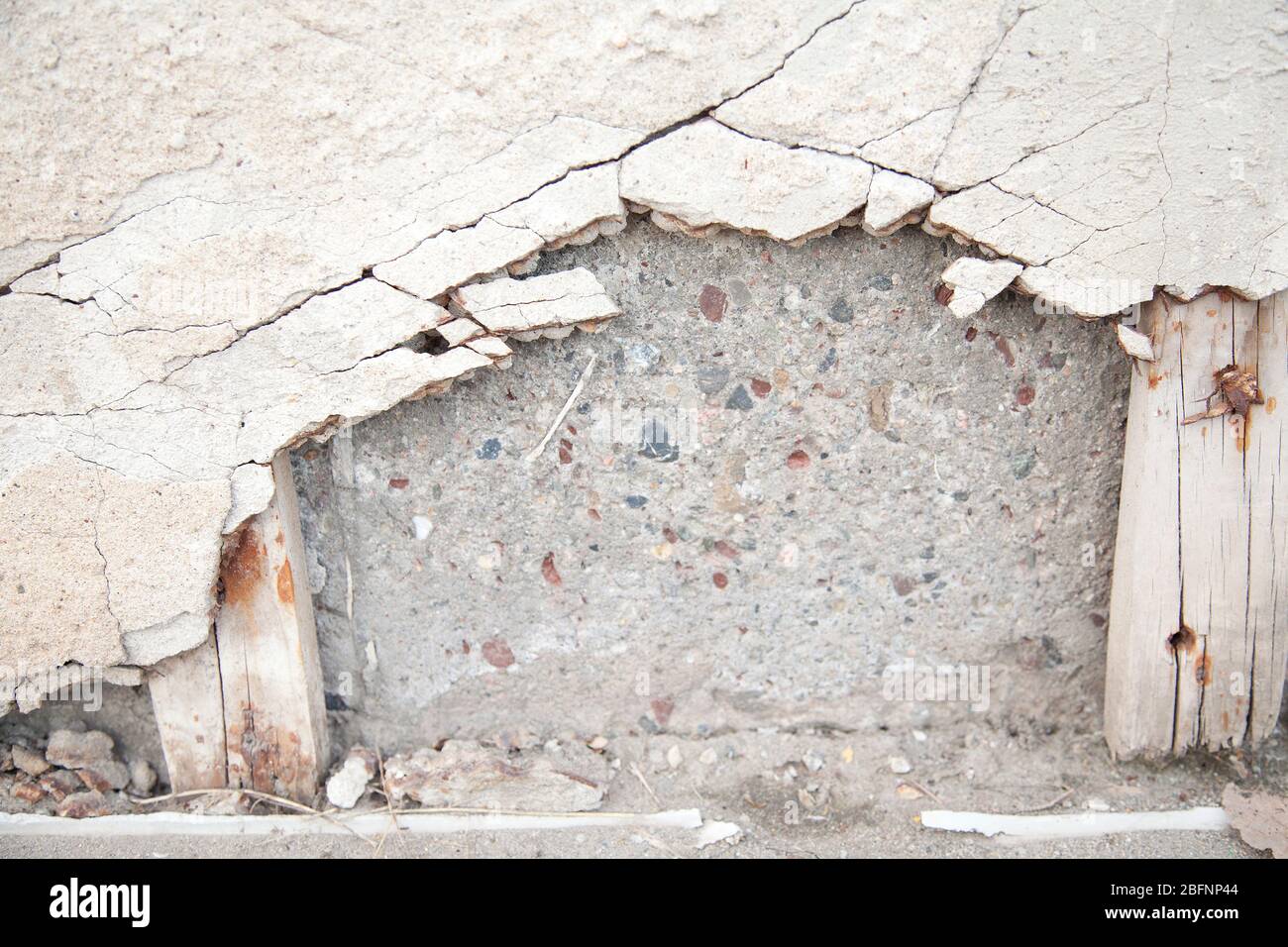 Zerbrochene Betondecke auf Schlackblöcken. Abgenutzter Zement, der von der Wand fällt. Strukturierter abstrakter Hintergrund. Stockfoto