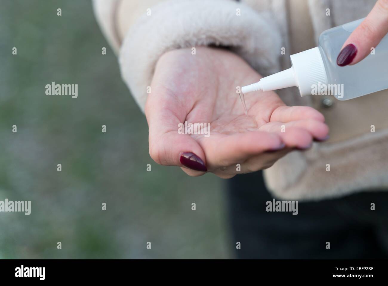 Mädchen behandelt Hände mit einem antiseptischen im Freien Stockfoto