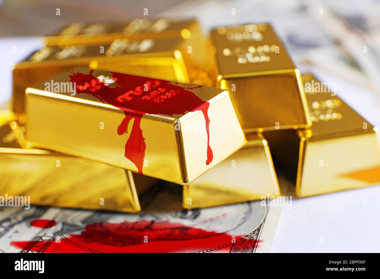 Goldbarren mit Dollar-Banknoten und Blutspritzern Stockfoto