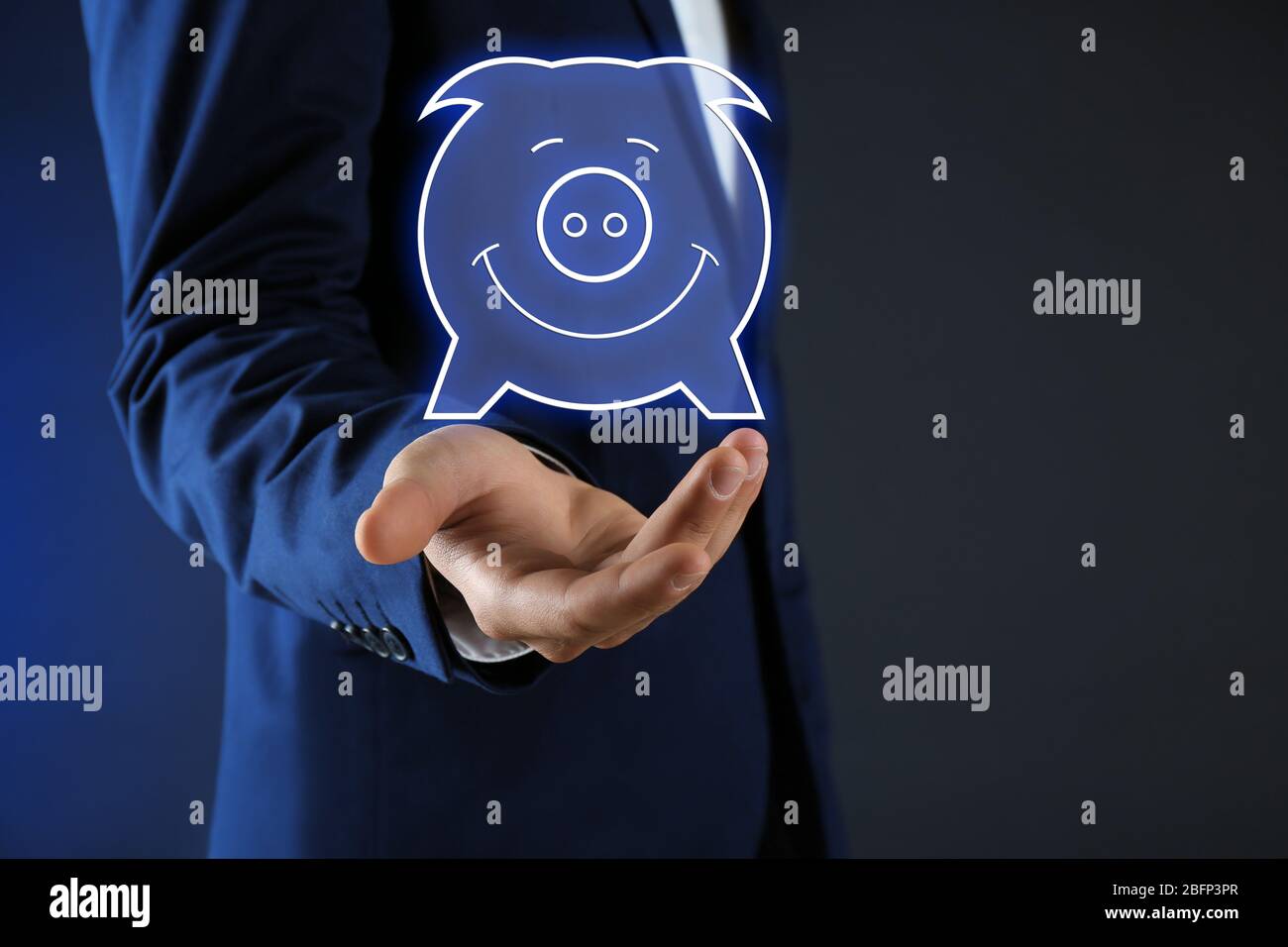 Geschäftsmann hält virtuelle Sparschwein auf dunklem Hintergrund Stockfoto