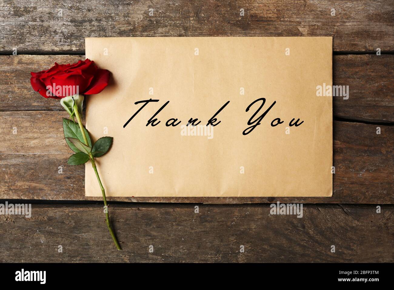 Karte mit Text Danke und schöne Rose auf Holzhintergrund Stockfoto