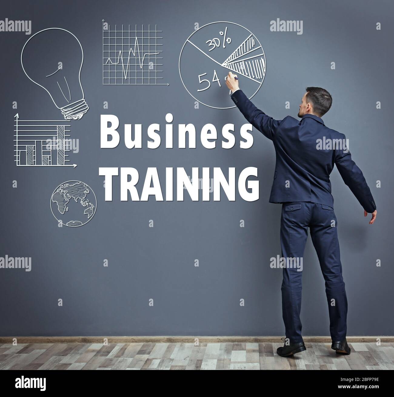 Business Training Konzept. Mann schreibt auf graue Wand Stockfoto