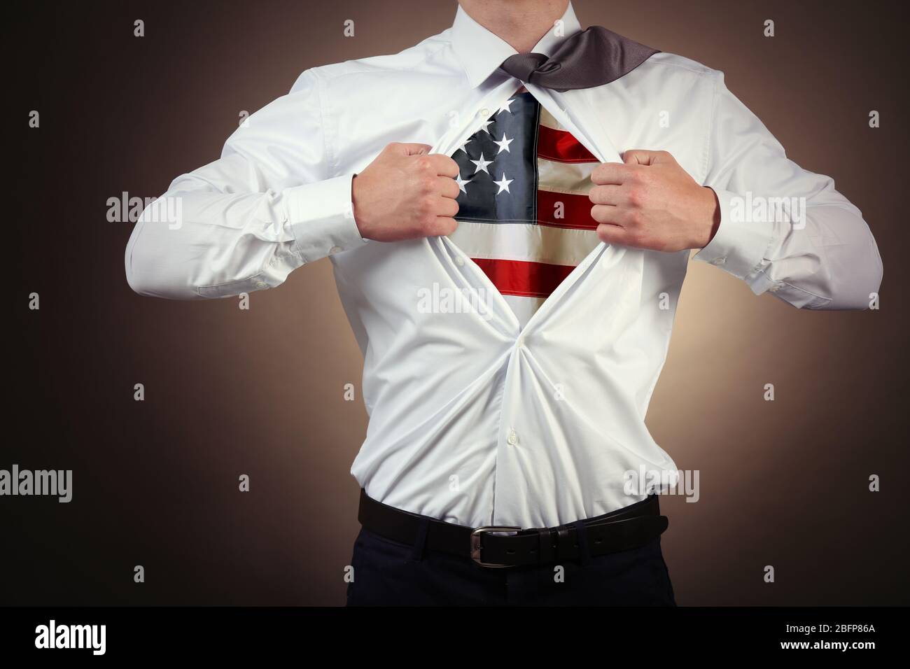 Geschäftsmann zeigt US-Flagge unter Anzug auf dunklem Hintergrund. Stockfoto