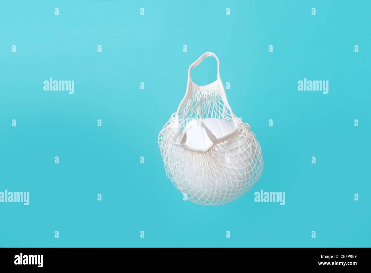 Weiße Netztasche mit Volleyball auf Luft. Blauer Hintergrund mit Kopierbereich. Stockfoto