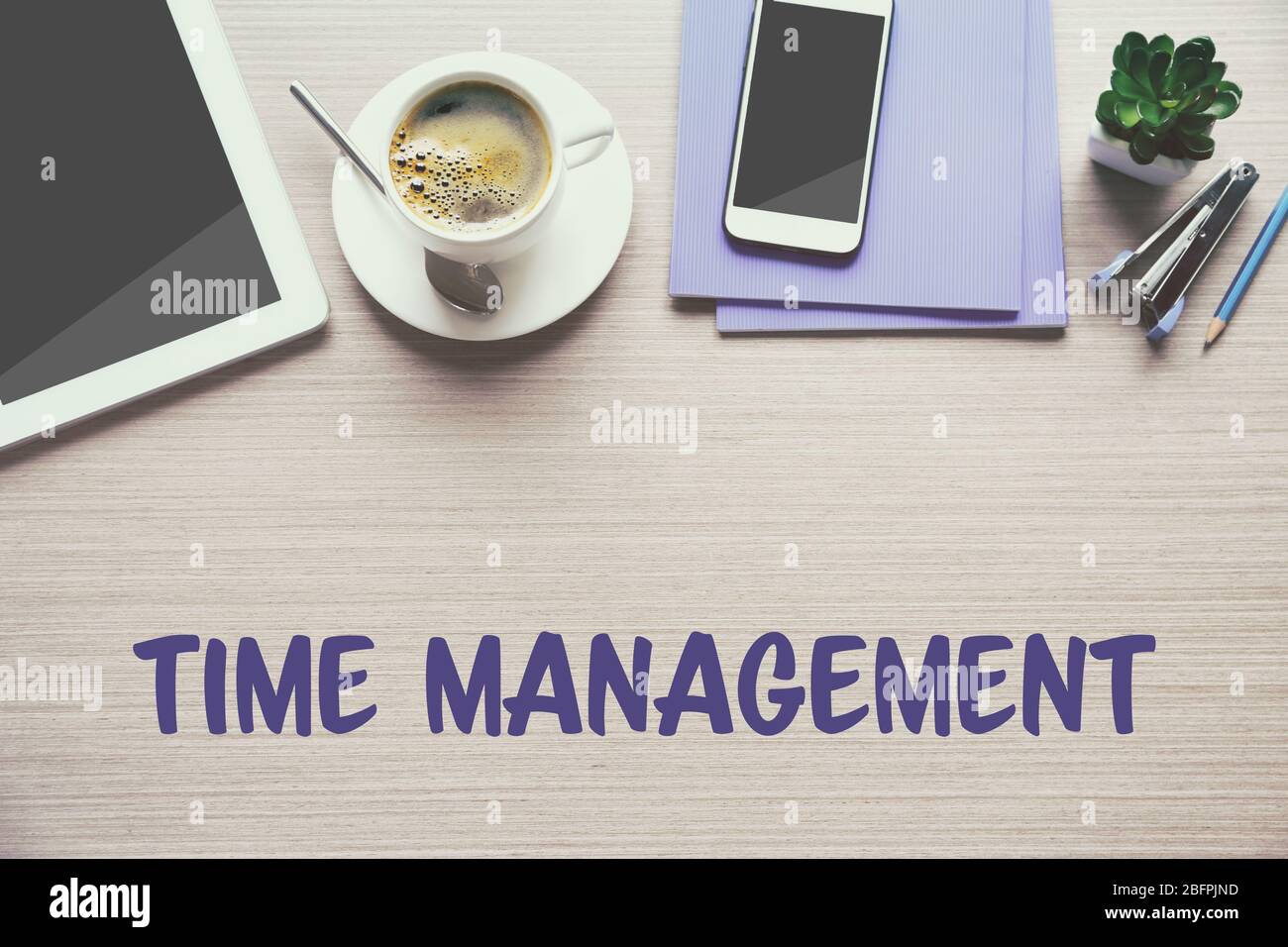 Konzept des Zeitmanagements. Tasse mit Getränk und Bürowerkzeug auf Holzhintergrund Stockfoto