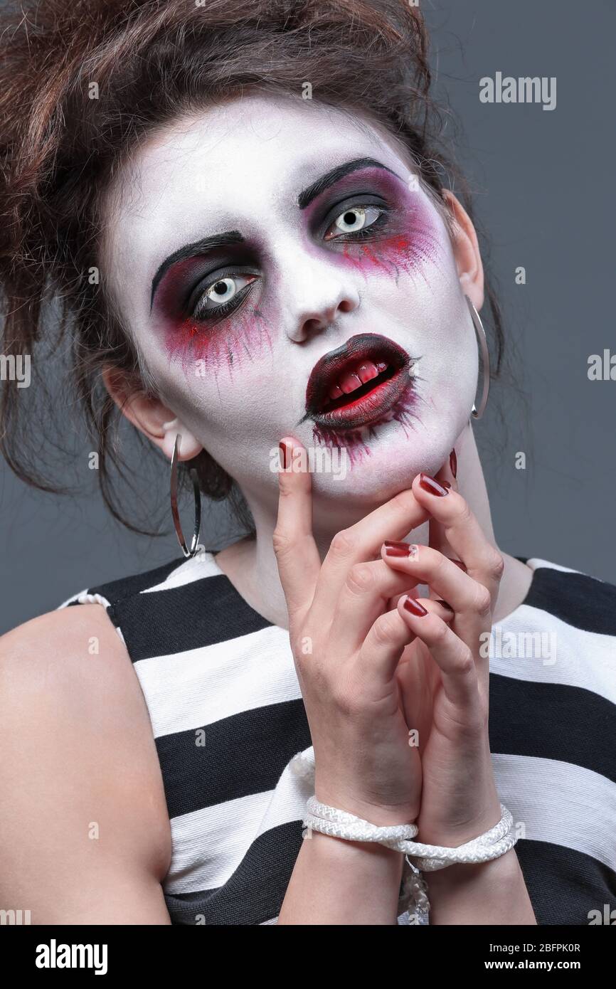 Junge Frau in farbigen Kontaktlinsen, mit Halloween Make-up auf grauem Hintergrund, Nahaufnahme Stockfoto