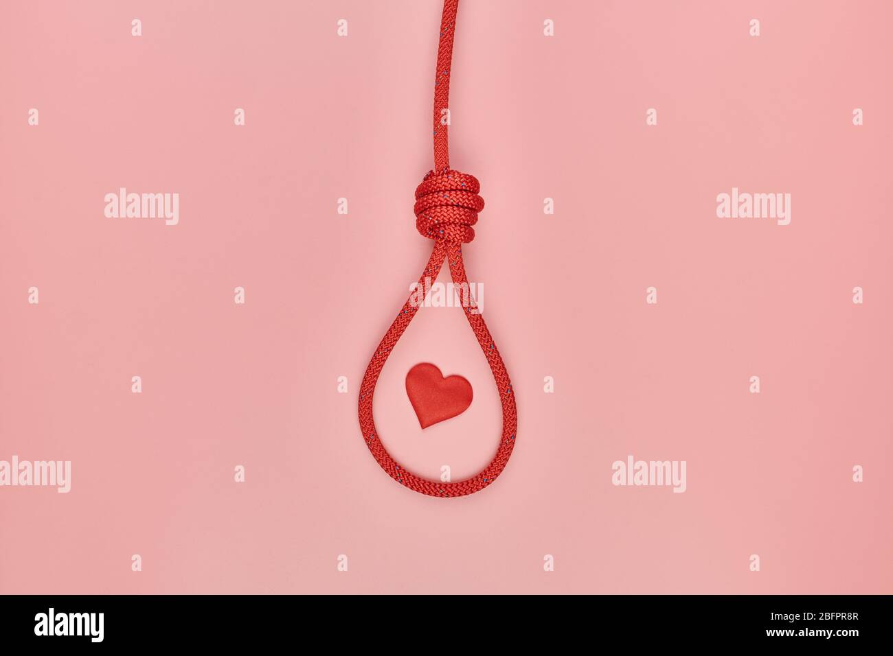 Herz im Knoten des Henkers. Unerhörte Liebe hängenden Selbstmord Konzept. Rote geflochtene Hängeschlinge Band den Knoten. Symbol für Valentinstag fehlgeschlagen Stockfoto