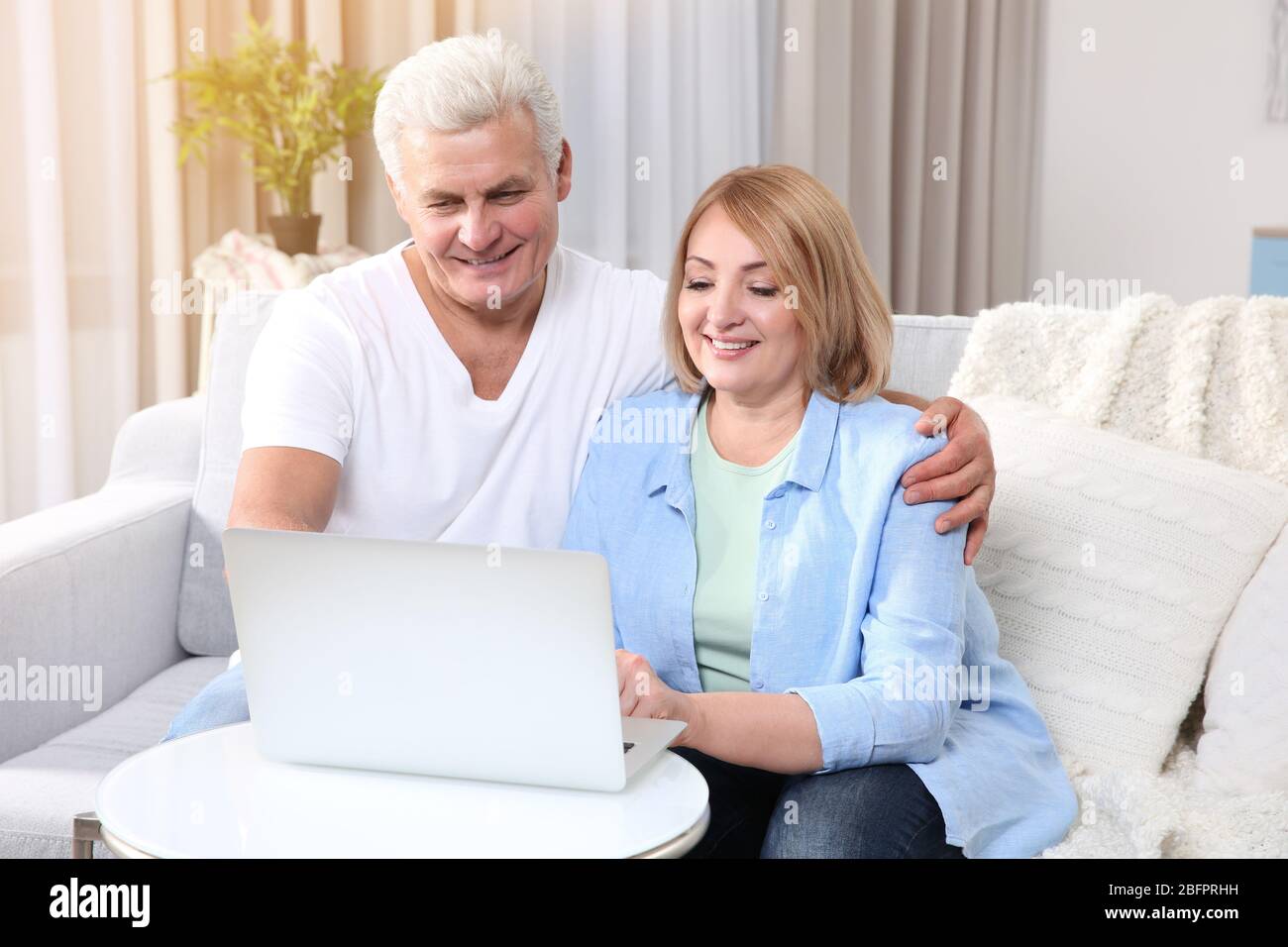 Seniorenpaar mit Laptop zum Surfen im Internet-Shop zu Hause. Online-Shopping-Konzept Stockfoto
