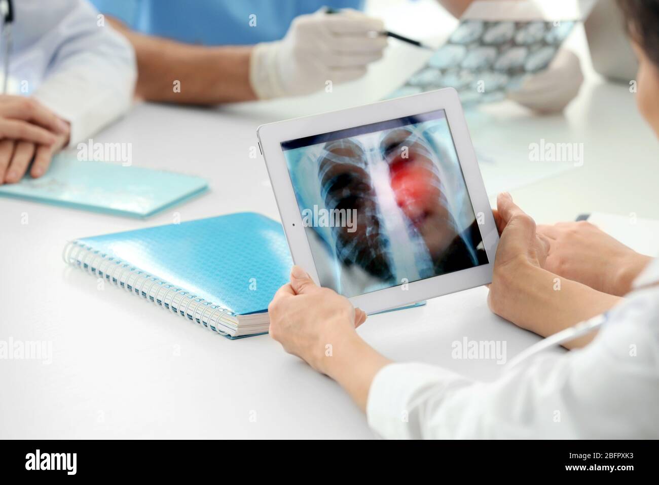 Arzt, der mit einem Tablet am Tisch im Krankenhaus arbeitet. Röntgenbild des Brustkorbs auf dem Bildschirm. Lungenkrebs Konzept Stockfoto