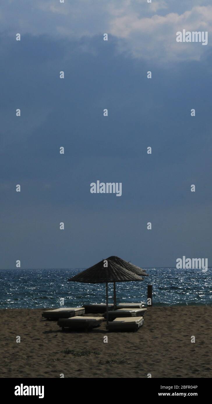 Leerer Strand und Sonnenschirme wegen Covid-19 vor Sturm Stockfoto