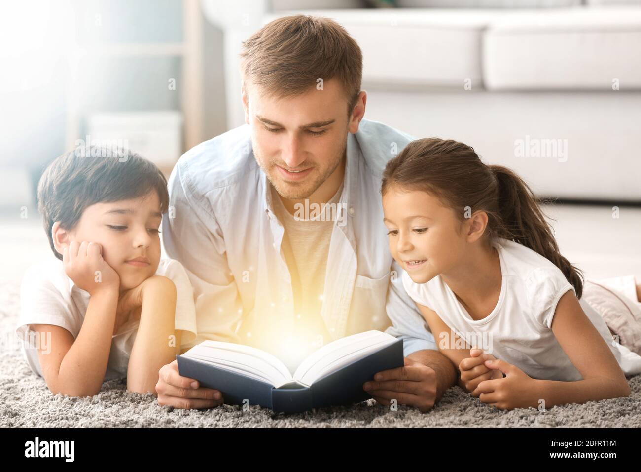 Vater und Kinder lesen zu Hause Buch Stockfoto