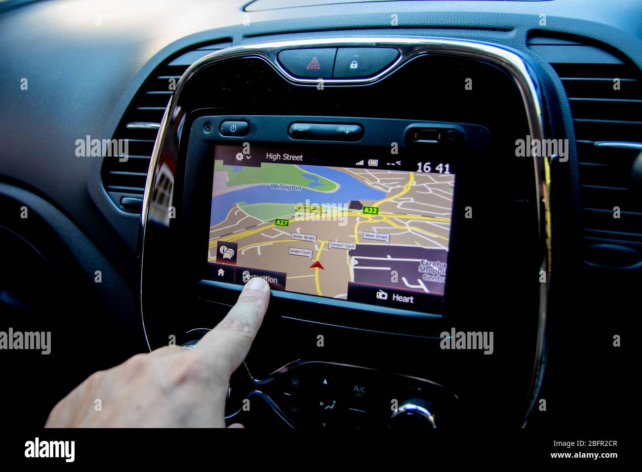 Nahaufnahme eines Fingers, der ein Navi oder eine Satellitennavigationseinheit im Auto bedienen kann Stockfoto