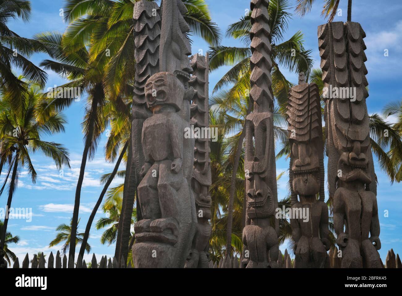 Die wilden Ki’i Statuen stehen Wache mit Blick auf die Honaunau Bay am Ort des Refuge National Historical Park auf der Big Island von Hawaii. Stockfoto