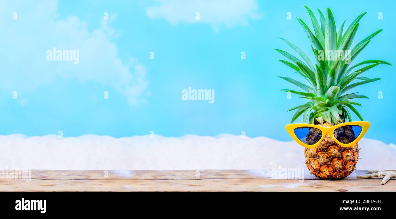 Ananas mit Sonnenbrille auf Holzhintergrund. Kreatives minimales Sommerferienkonzept Stockfoto