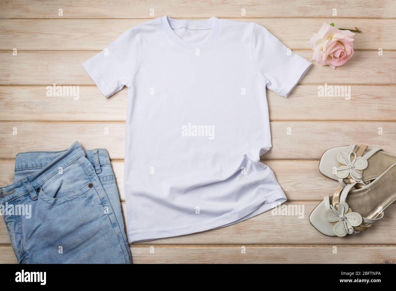 Weißes Damen-T-Shirt aus Baumwolle mit rosa Rosen, blauen Jeans und offenen Zehensandalen. Design T-Shirt Vorlage, T-Print Präsentation Mock up Stockfoto