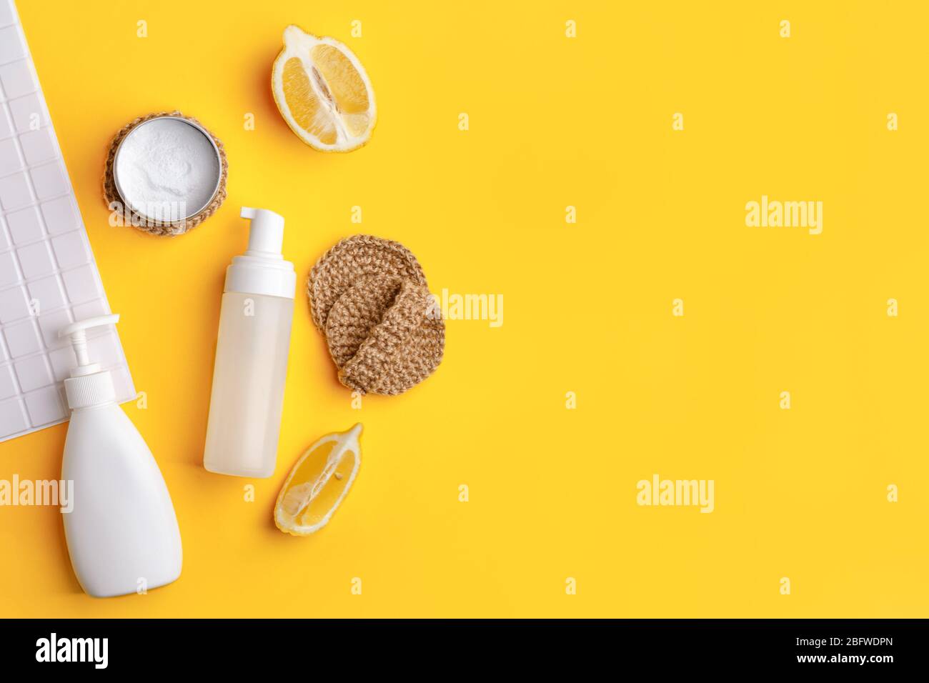 Set von umweltfreundlichen natürlichen Reinigungsmittel auf gelben Küchentisch: Soda, ätherische Öle, Zelluloseschwamm, Lumpen, Zitrone, Seife, Essig. Keine Verschwendung, Stockfoto