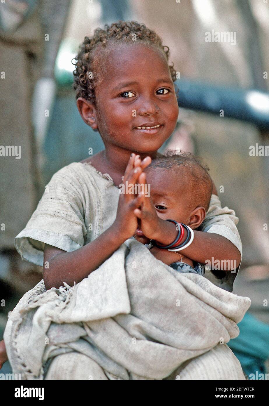 Ein somalischer Mädchen, dass ein Kind darauf wartet, von einem Navy corpsman untersucht werden. Bekämpfung Service Support Abteilung 15 (CSSD-15) ist die Durchführung einer medizinischen civic Aktionsprogramm während der multinationalen Entlastung Bemühung Operation Restore Hope. Stockfoto
