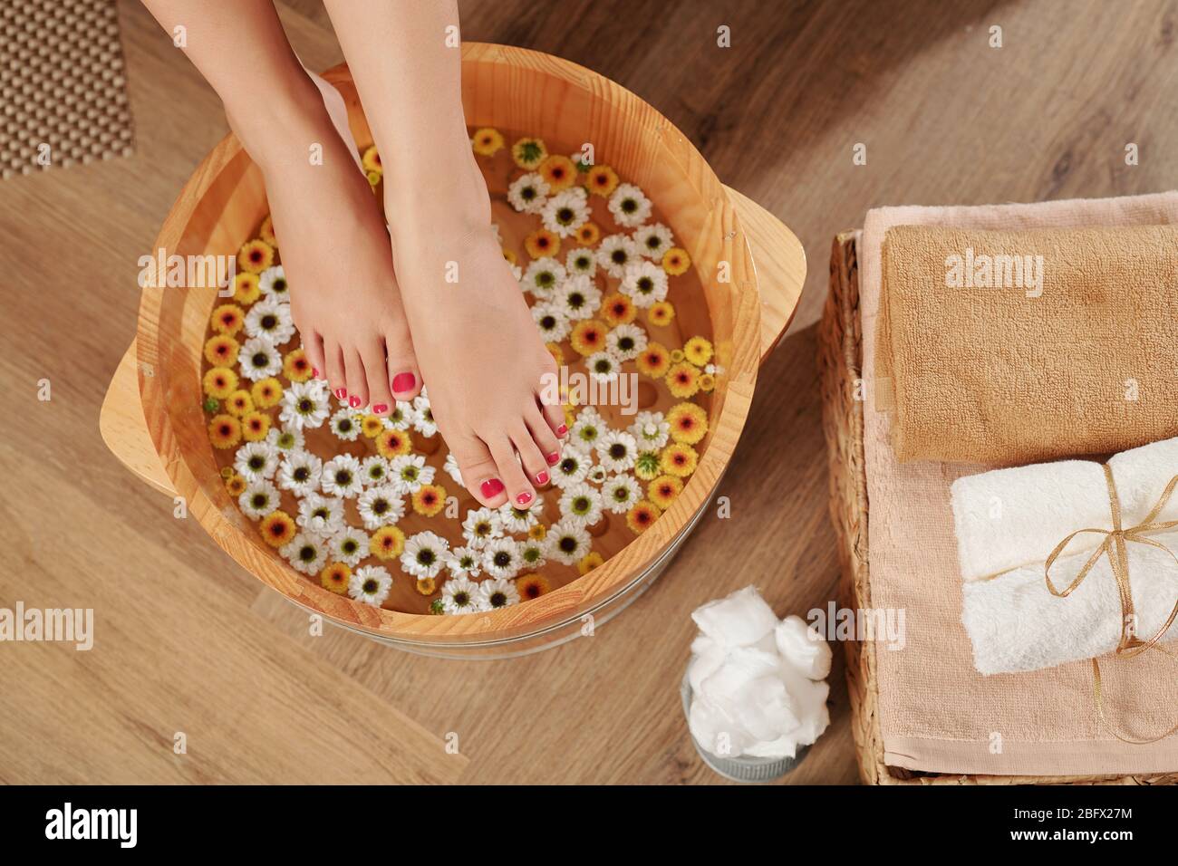 Frau, die mit Pediküren Füßen in ein Becken mit warmem Wasser setzt, um sich nach einem langen Tag zu entspannen Stockfoto