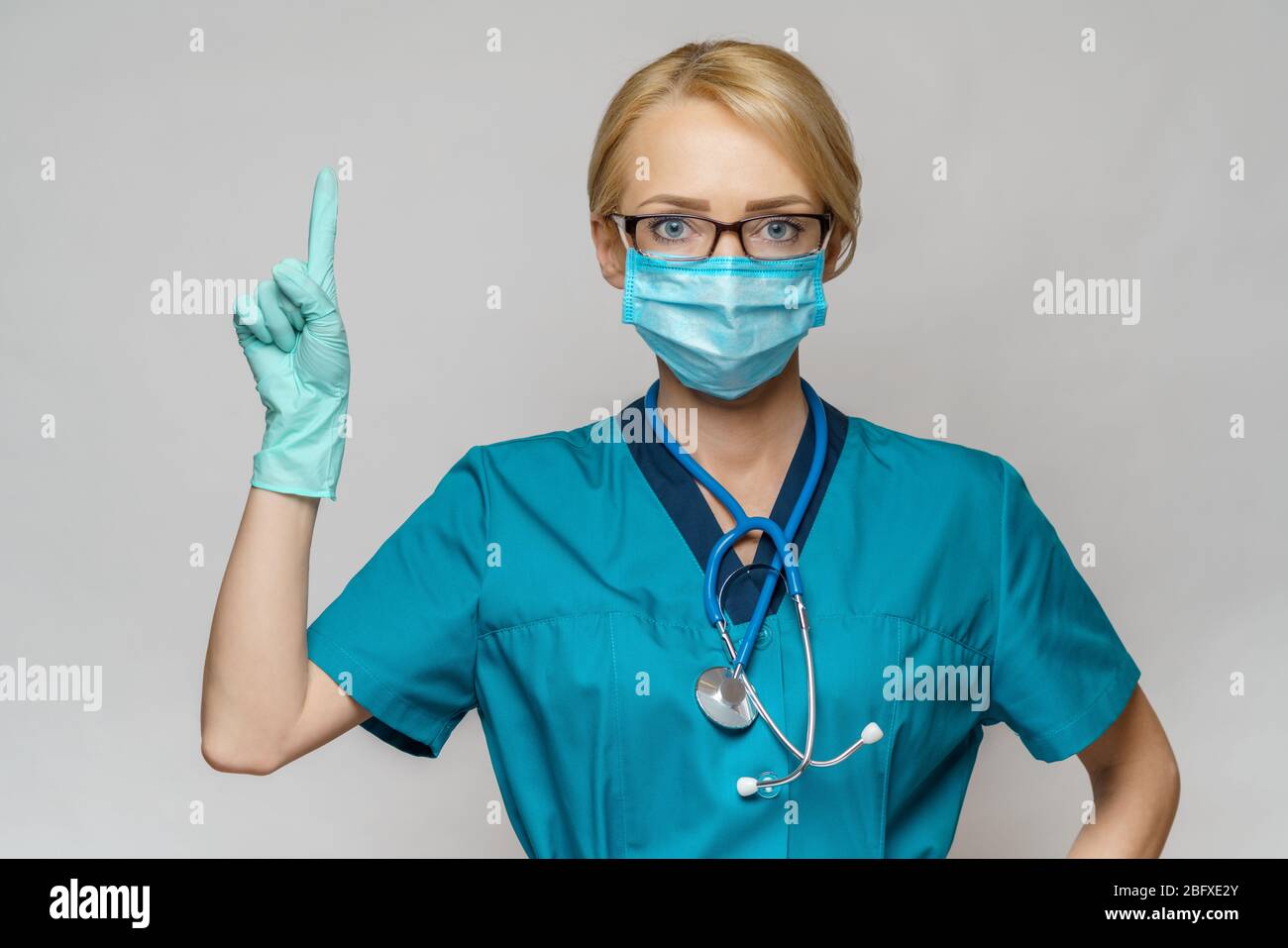 Arzt Krankenschwester Frau mit Schutzmaske und Latexhandschuhe - Zeigen Sie mit dem Finger auf leere Kopiefläche Stockfoto