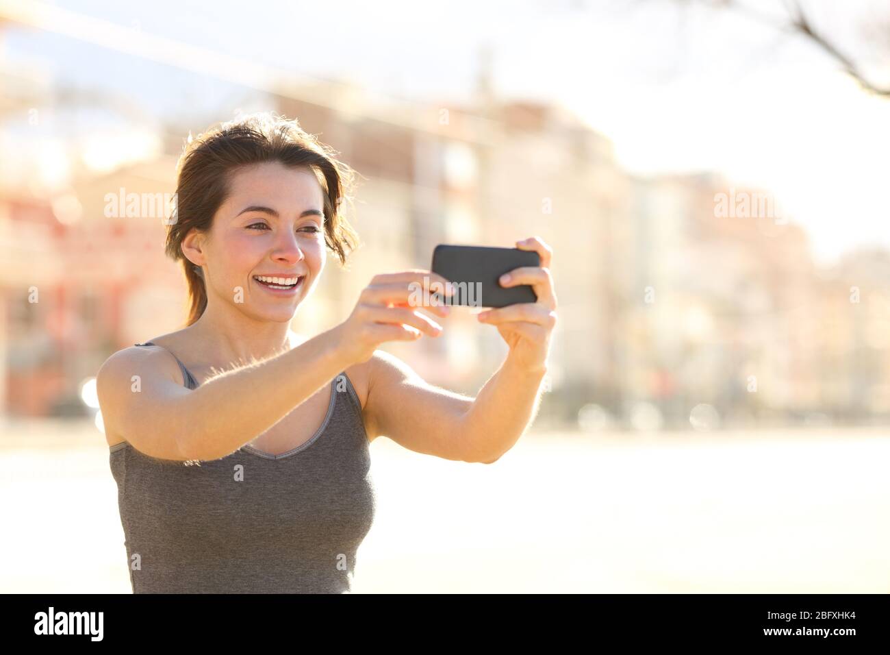 Glückliche Frau, die Selfie mit Smartphone nimmt, lächelt auf der Straße Stockfoto